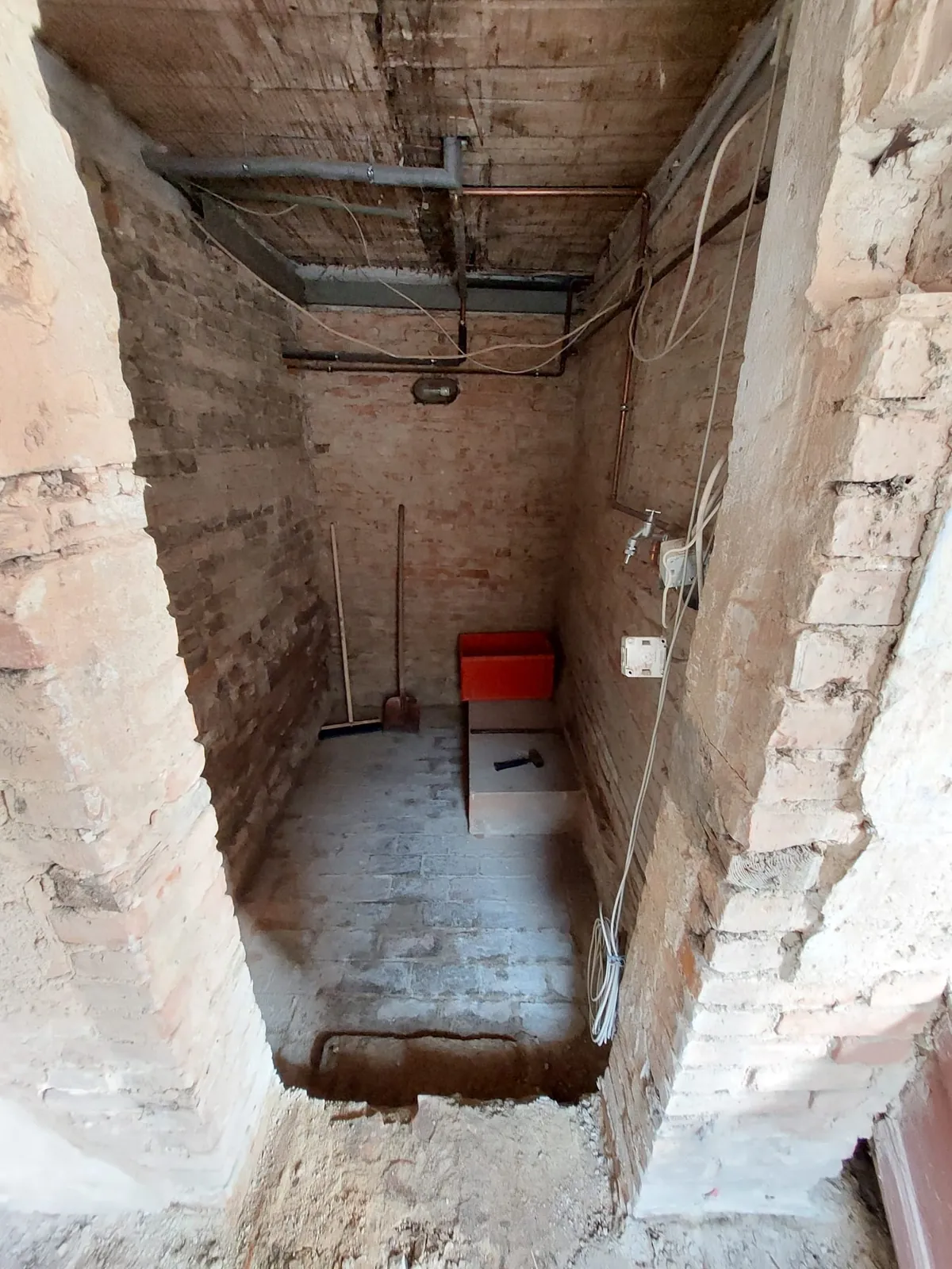 Entkernter Raum mit Ziegelwänden und neuen Kupferleitungen an der Decke
