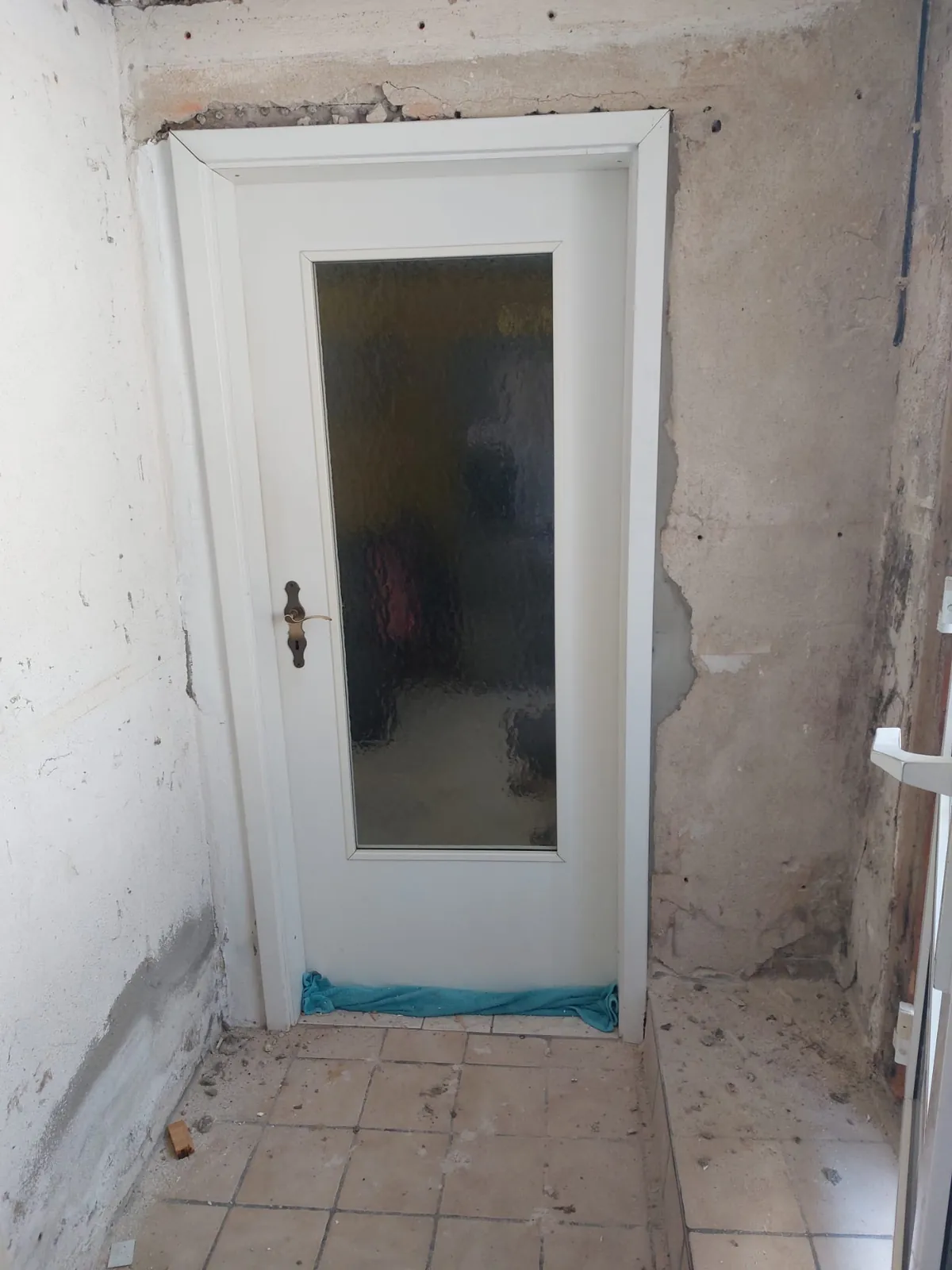 Weiße Innentür mit Strukturglas vor entkernten Wänden im Altbau