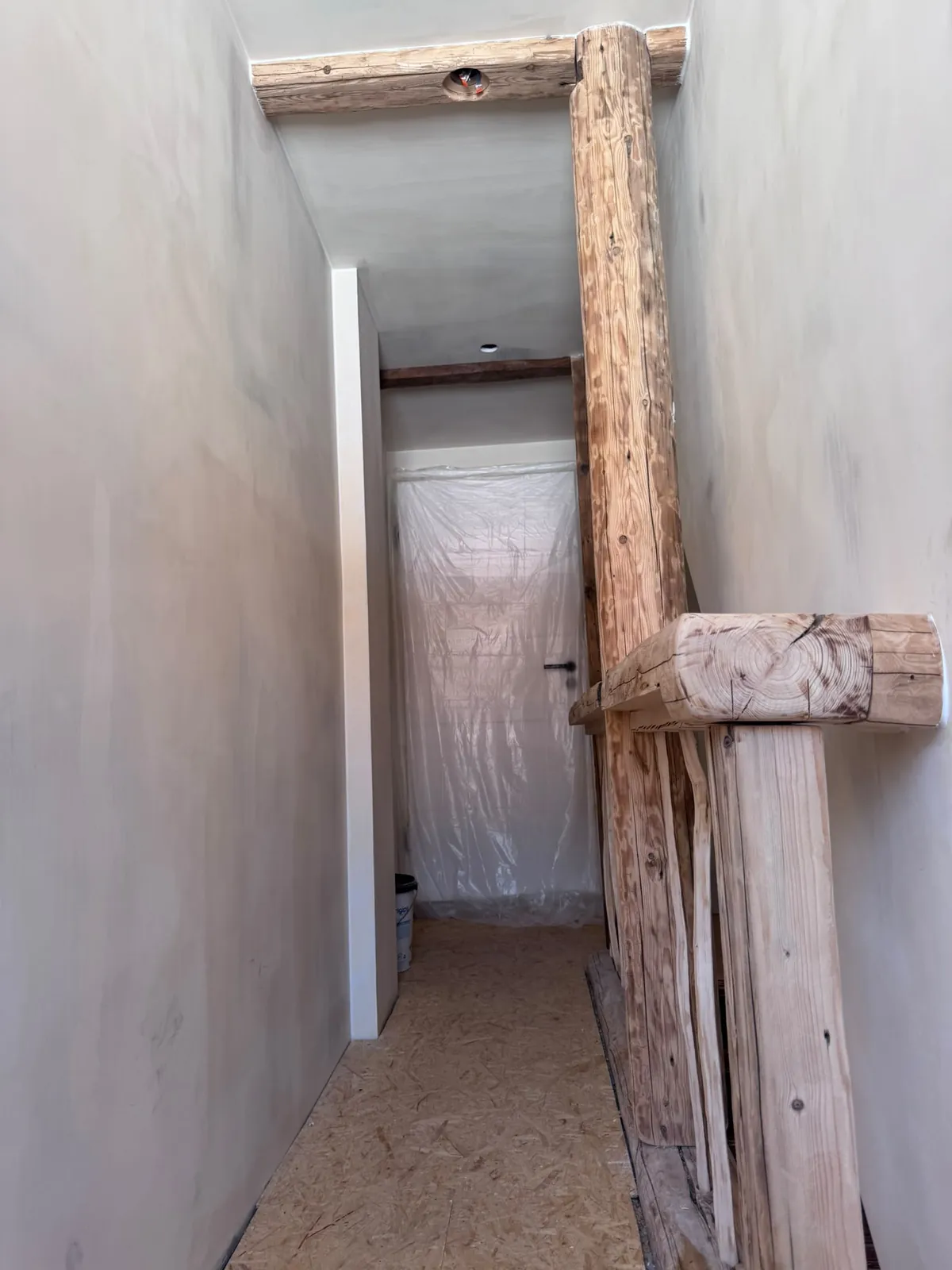 Verputzter Flur im Obergeschoss mit Holzpfosten und Altholz-Geländer
